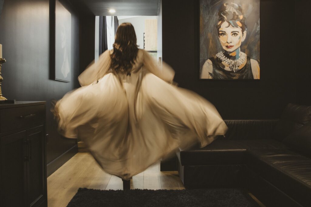 Ava Marie, resplendent in her elegant gown, twirls gracefully in a stylishly adorned room. Her rhythm echoes the enchanting dance movement, frozen in time like a stationary ballet performance while an intriguing portrait quietly observes from the backdrop. Ava Marie Halifax's Elite Independent Companion
